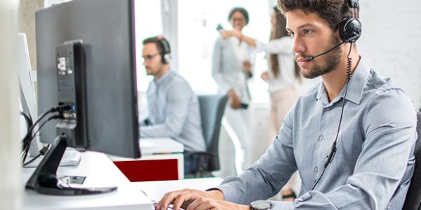 Young handsome male customer support phone operator with headset working in call center.